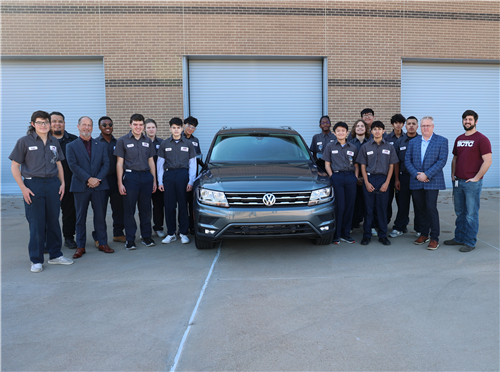 Students and adults standing around a car